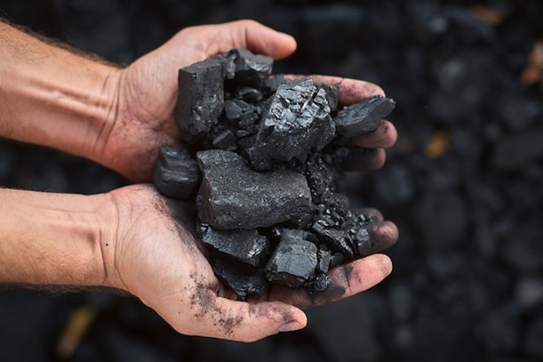 Photo poor middle-aged man holding the hands of stone coal